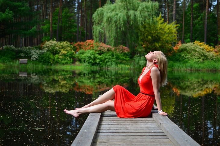 Žena u crvenoj haljini na obali jezera.