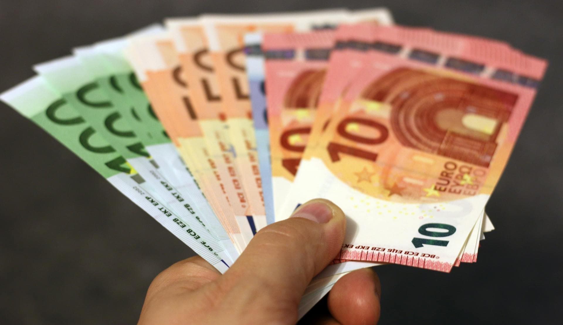 Čovek drži više novčanica eura