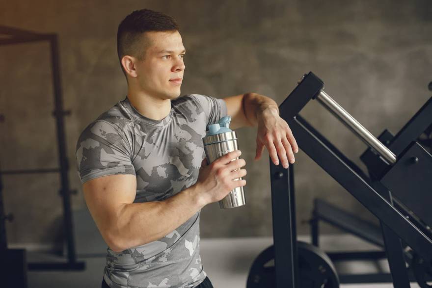 Čovek u teretani pije protein šejk