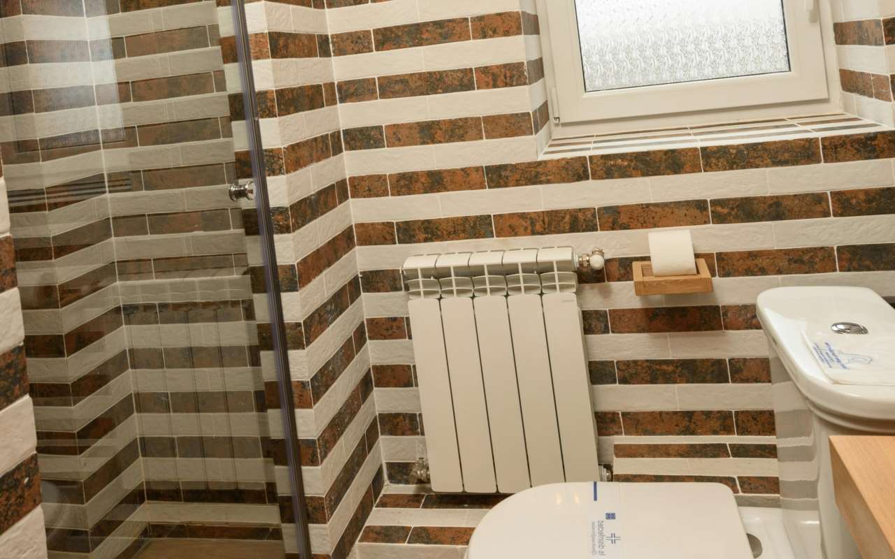 Malo kupatilo sa WC šoljom, tuš kabinom, lababoom i malim prozorom