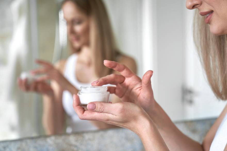 Devojka koristi anti-age kremu u kupatilu